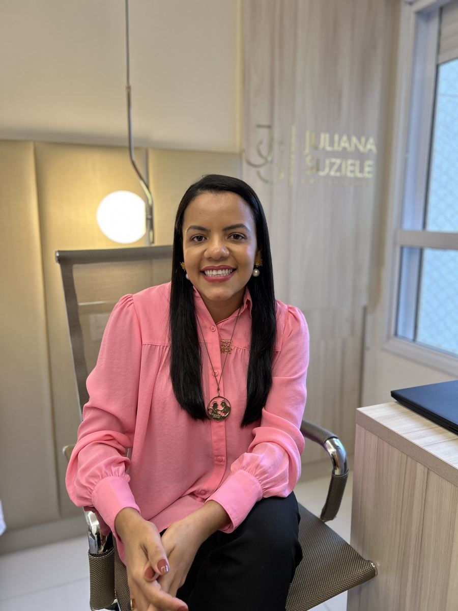 Juliana Suziele sentada em seu escritório, com o nome dela na parede ao fundo