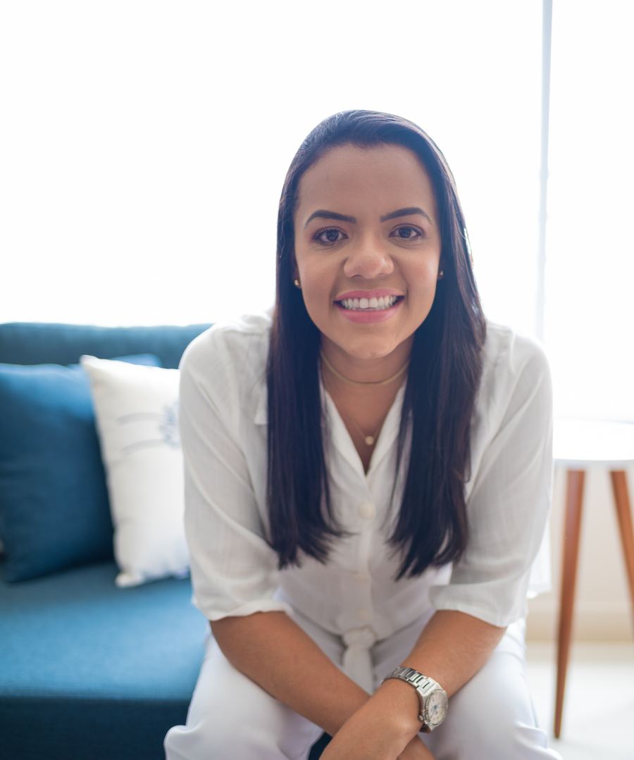 Juliana Suziele, de branco, sentada em um sofá